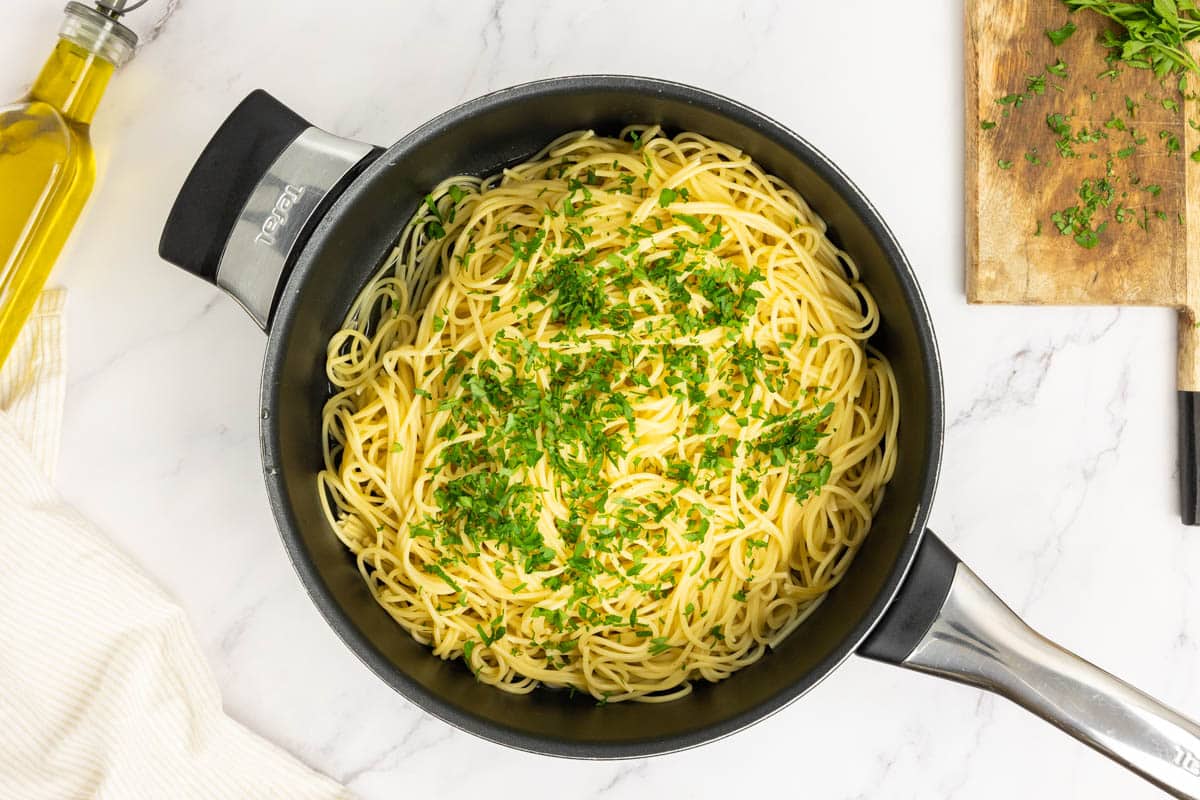 Adding pasta and fresh parsley to the garlic oil