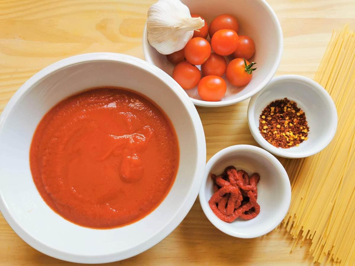 Ingredients for assassin's spaghetti spaghetti all'assassina in white bowls on wood surface.