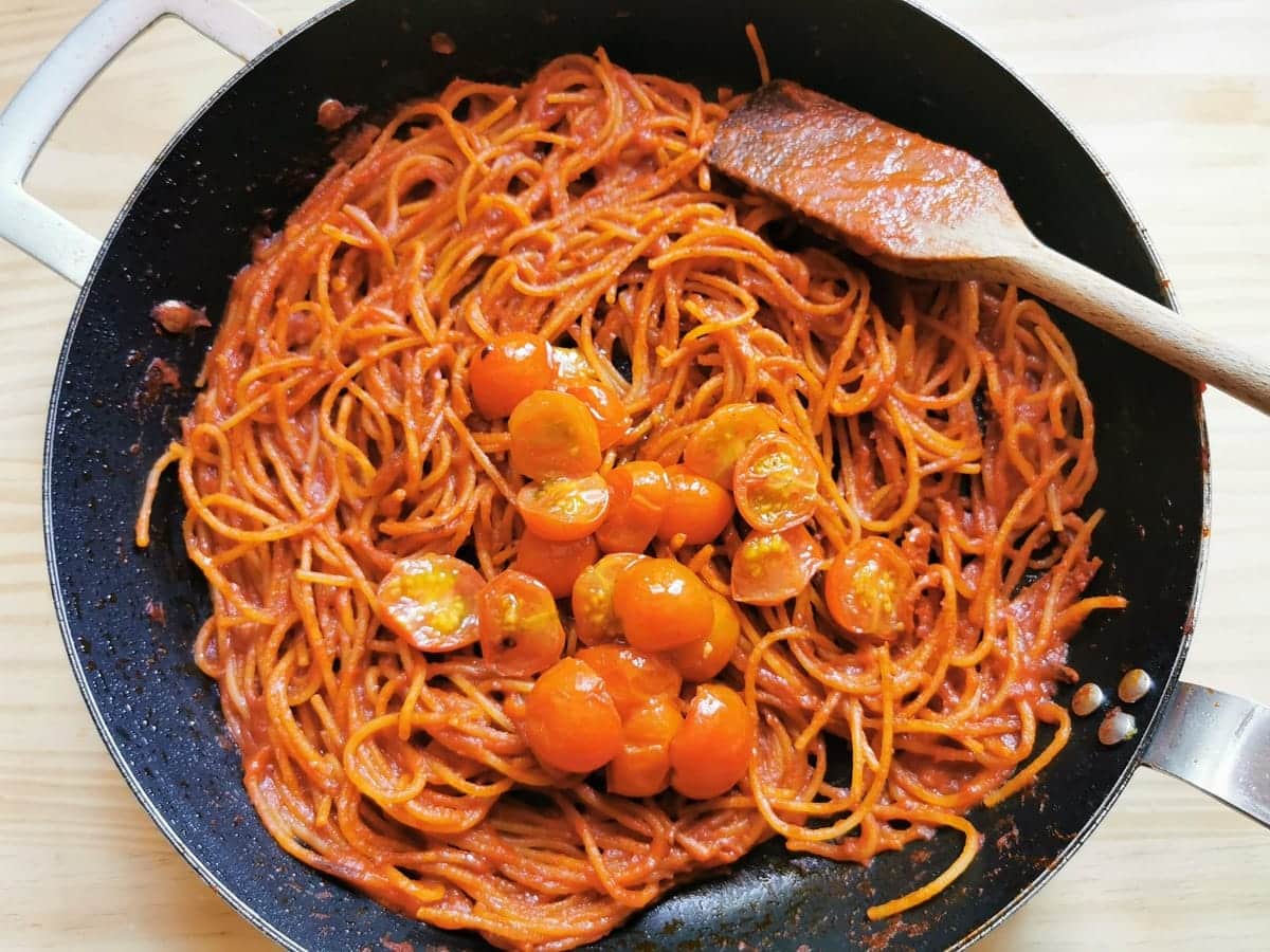 cooked cherry tomatoes in skillet with spaghetti all'assassina