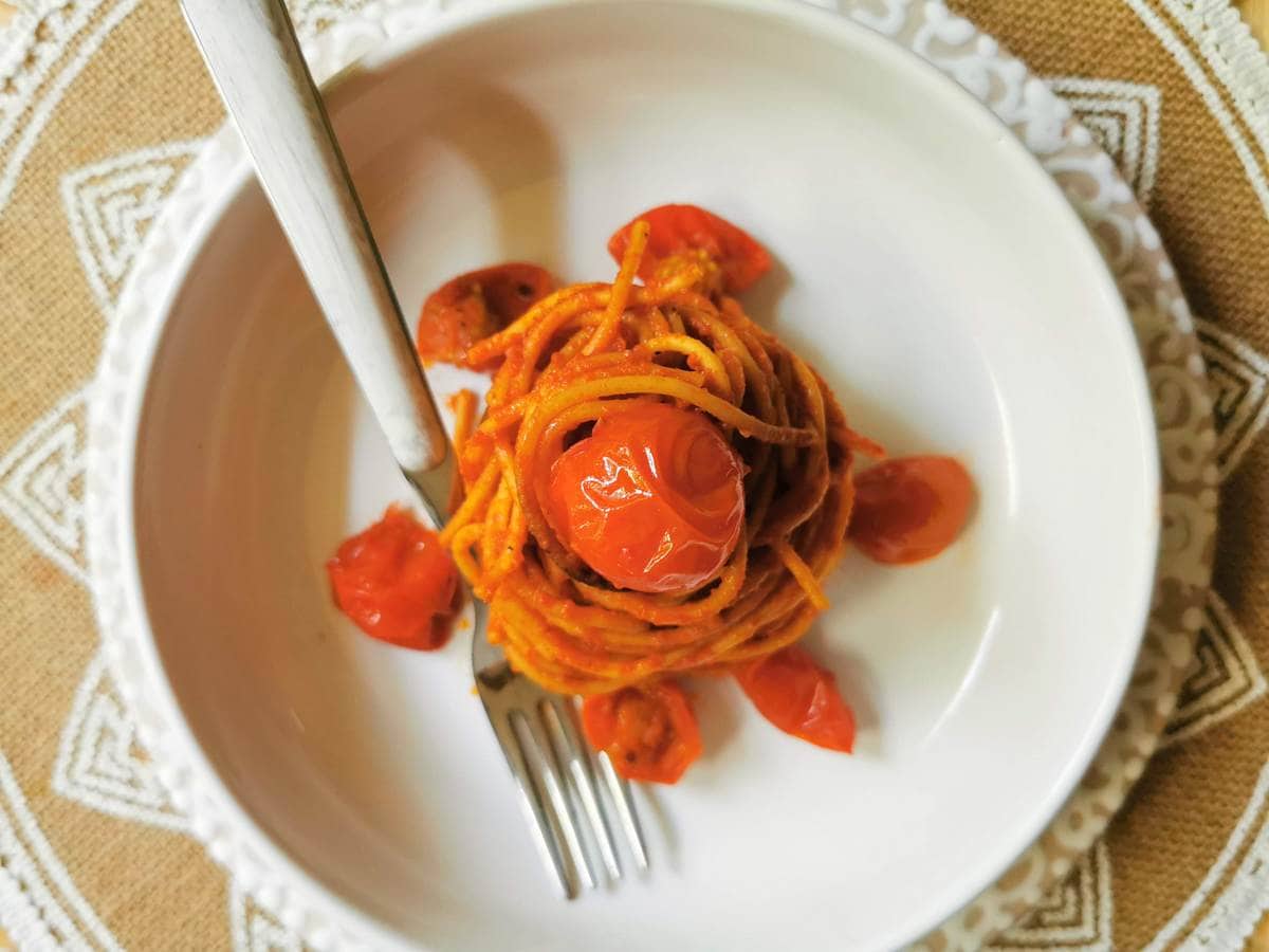 spaghetti all'assassina (assassin's spaghetti) in white bowl with cherry tomatoes