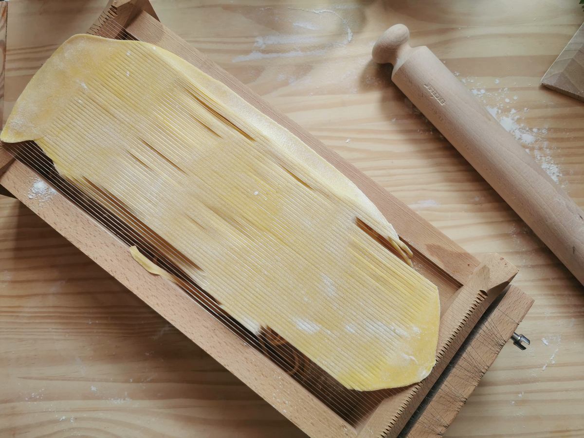 Spaghetti alla chitarra being made with a chitarra pasta tool.
