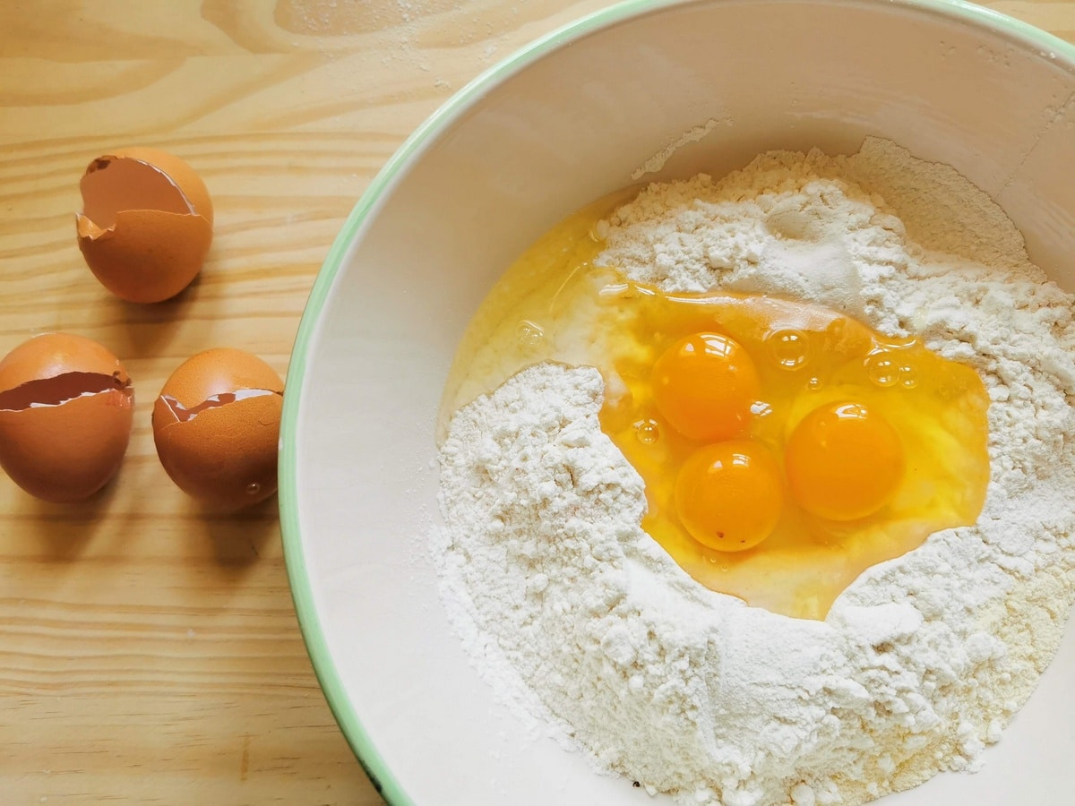 Two types of flour in a bowl with 3 eggs.
