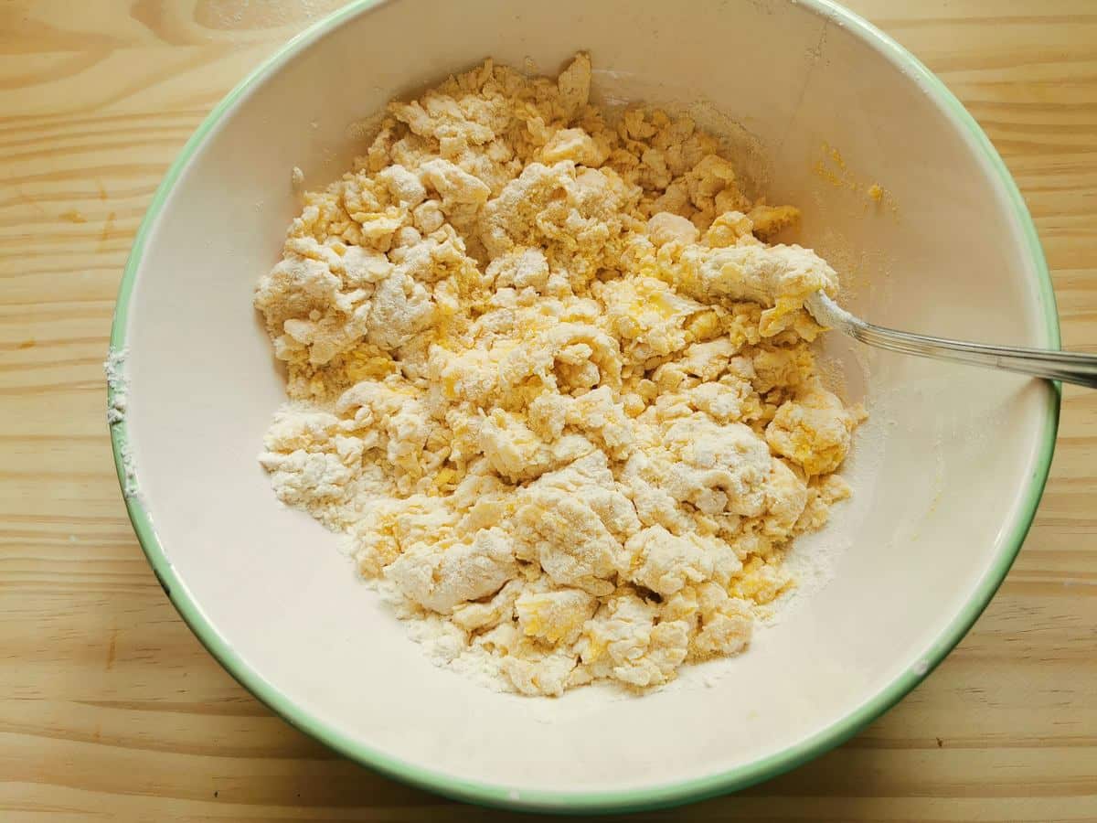 Eggs and flour mixed together in a bowl with a fork.