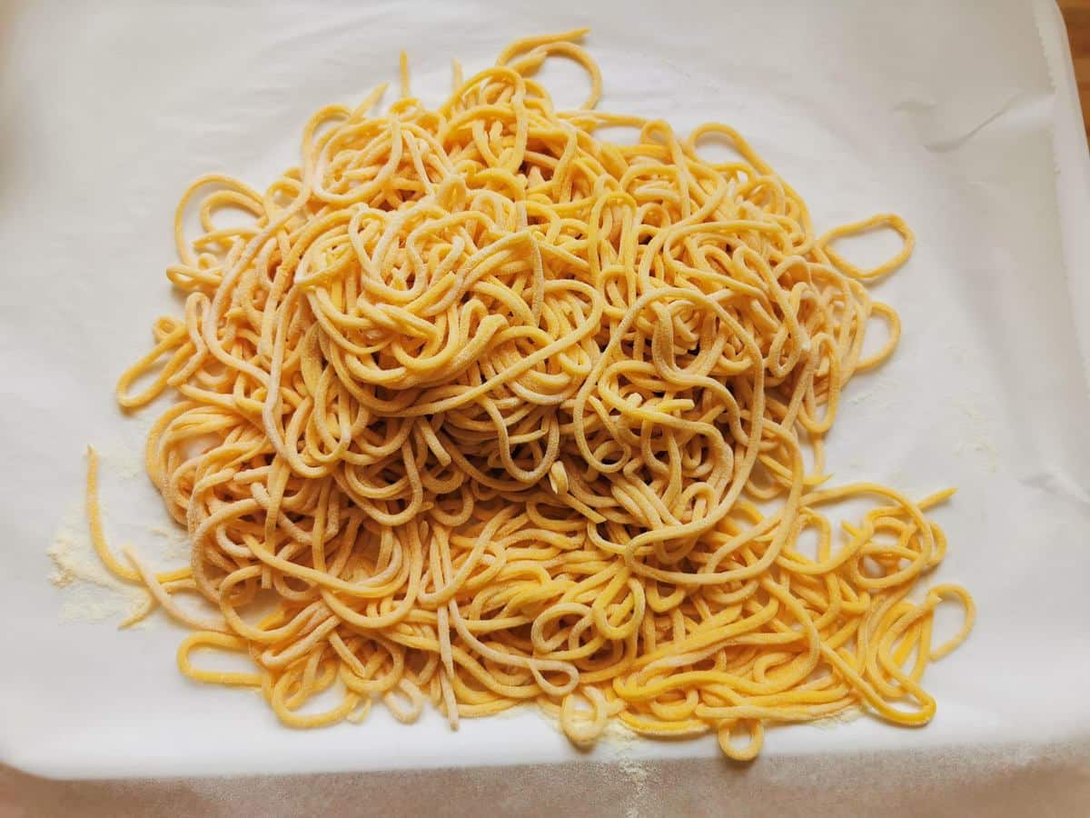 Ready homemade spaghetti alla chitarra on a sheet of baking papaer.