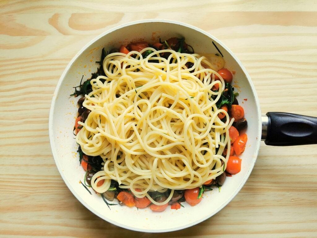 cooked spaghetti alla chitarra (chitarrine) in frying pan with sauce