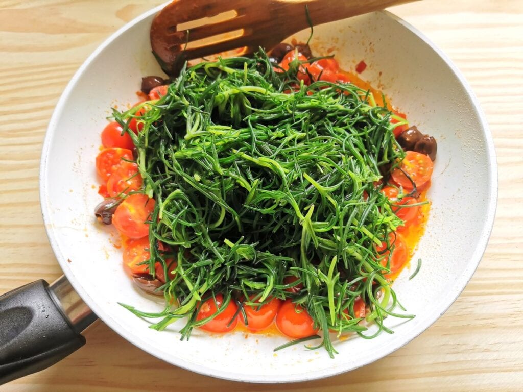 Blanched agretti in frying pan with other sauce ingredients