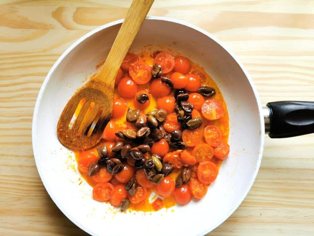 Pitted olives added to pan with tomatoes