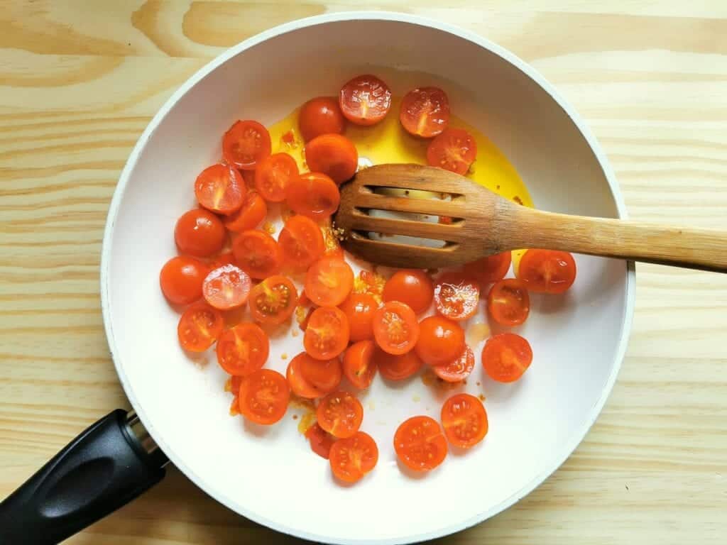 Cherry tomato halves in pan with garlic and peperoncino