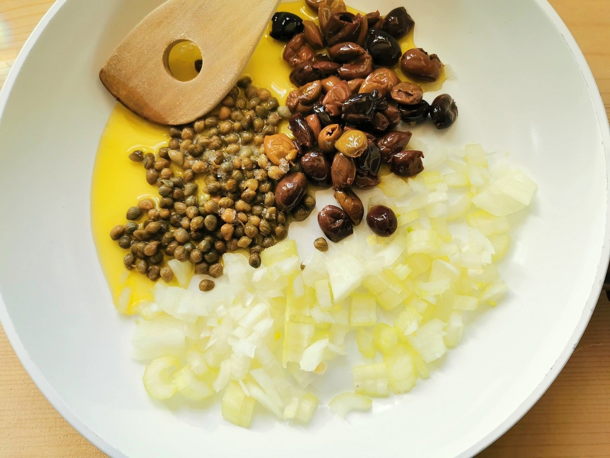 onion, celery, olives and capers in frying pan with olive oil