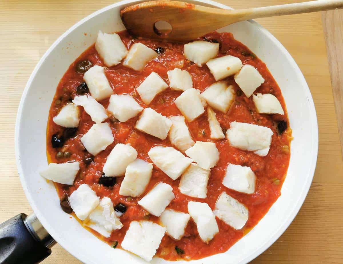 cubes of baccalà salt cod added to sauce in frying pan