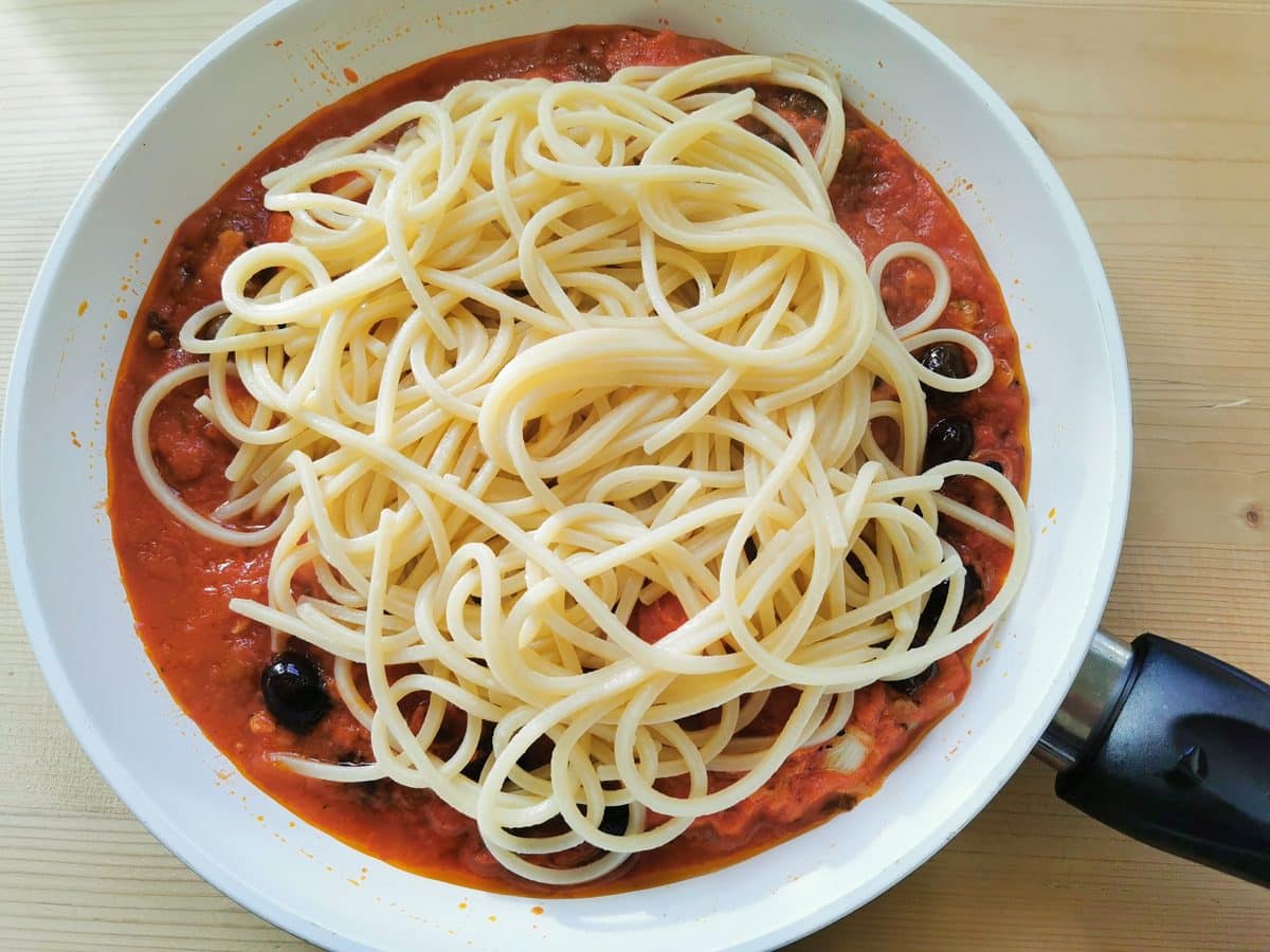 Cooked spaghetti added to the salt cod sauce