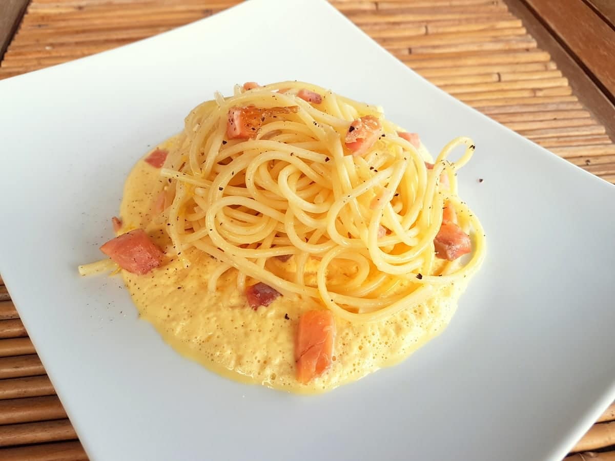 Smoked trout carbonara on a plate garnished with black pepper.