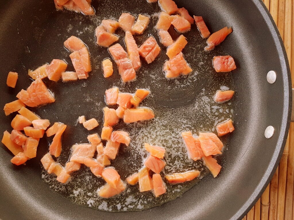 pieces of smoked trout frying in butter in skillet