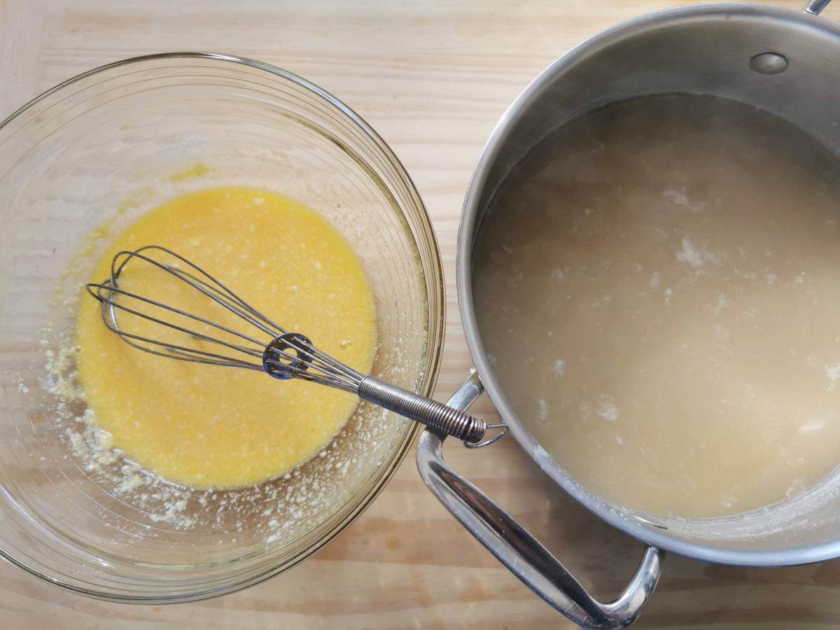Egg and cheese mixture in glass bowl next to pot of hot beef broth.