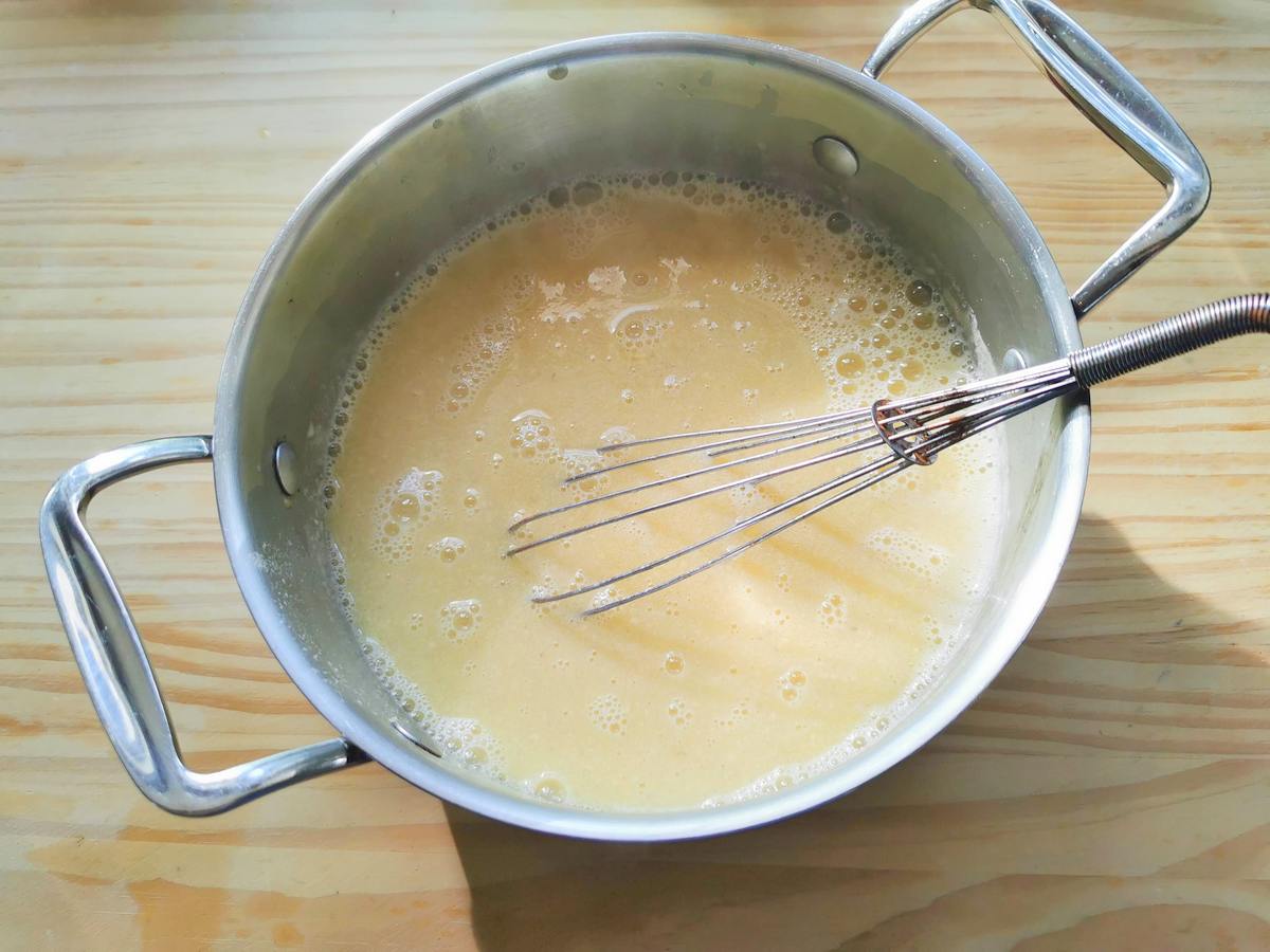 Stracchiatella soup in pot with a whisk.