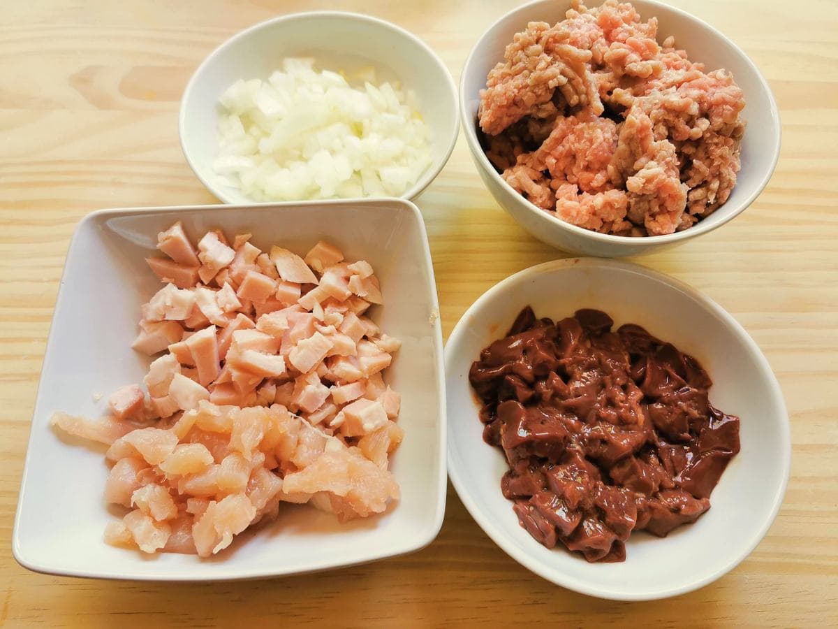 ground veal, chopped onion and chopped chicken livers, turkey breast aand ham in separate white bowls