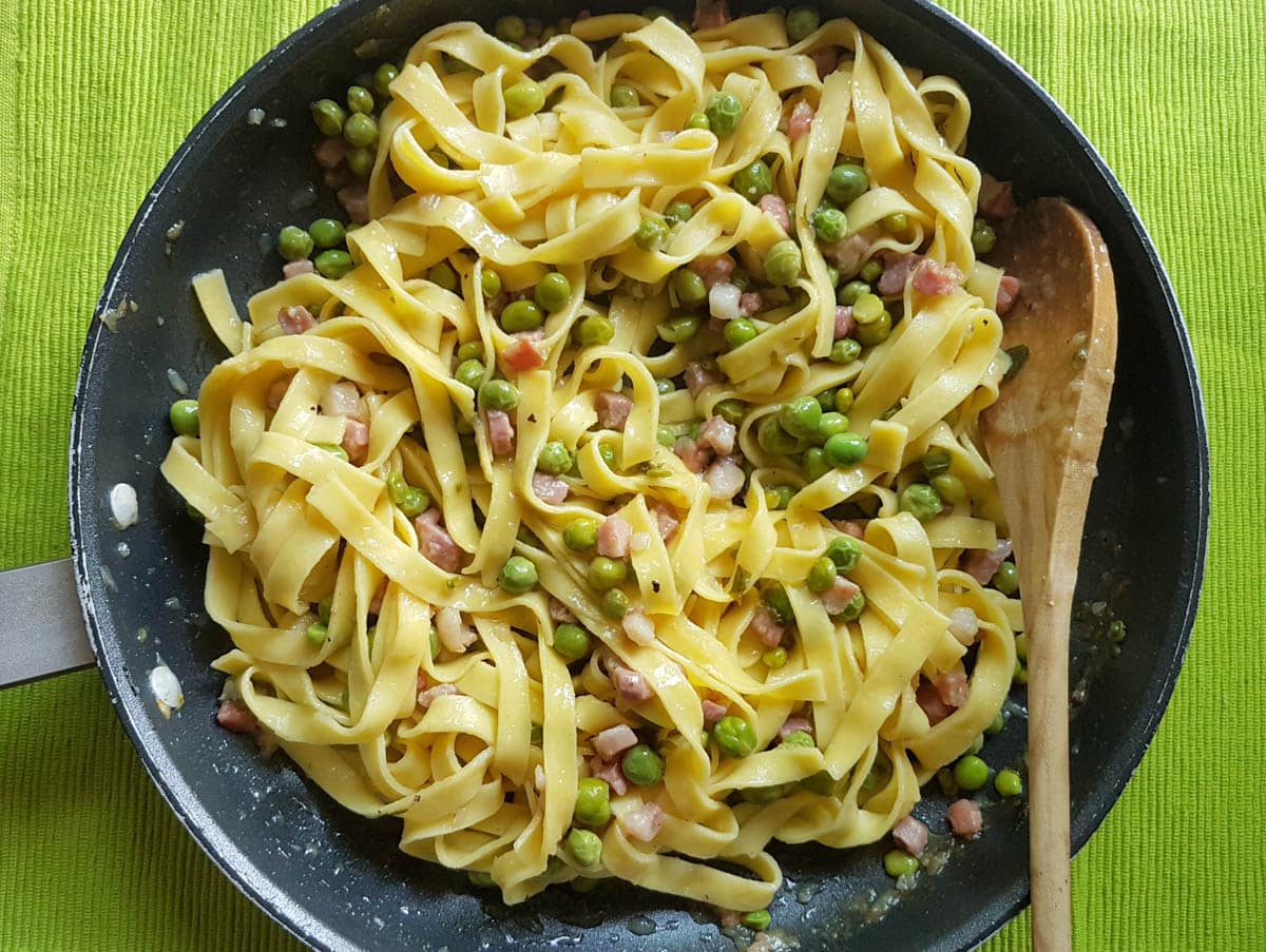 Tagliatelle pasta with fresh peas and pancetta that has been mixed with butter and parmesan