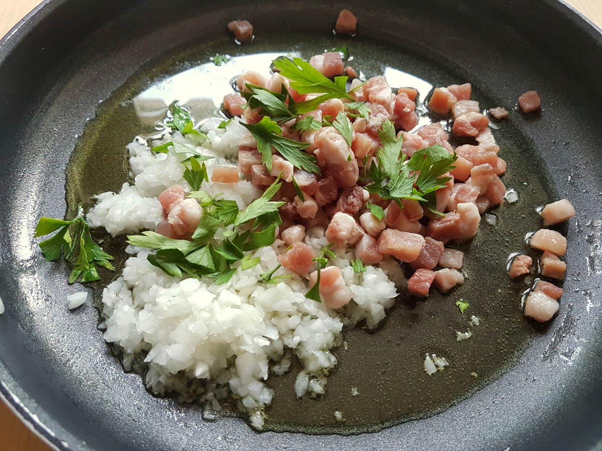 Chopped onion, pancetta and parsley in frying pan with olive oil