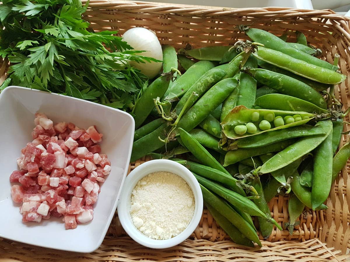 Peas, pancetta, onion, parsley and parmesan in a wooden basket.