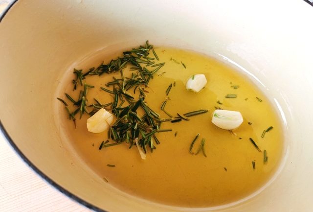 peeled garlic and rosemary cooking in Dutch oven