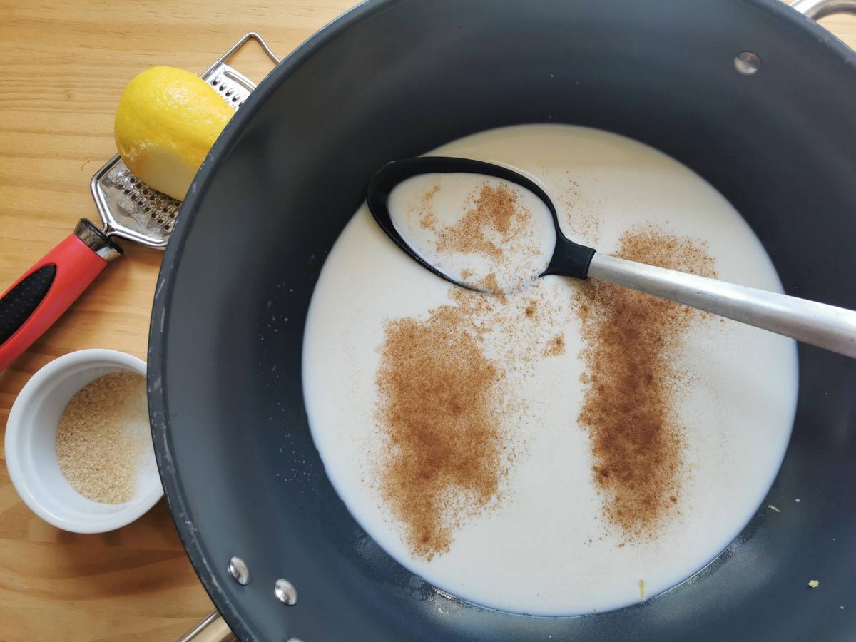 Fresh cow's milk in deep skillet with lemon zest, cinnamon powder, brown sugar and salt.