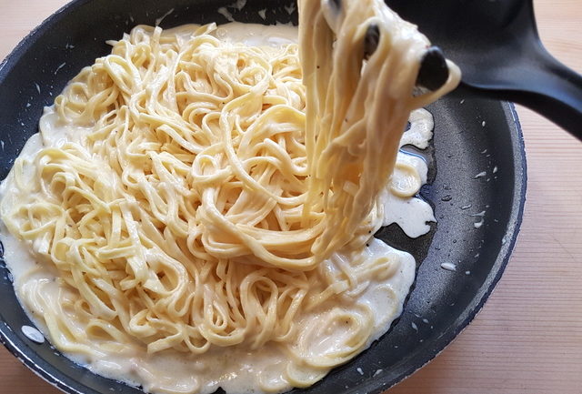 Taleggio cheese sauce and tagliolini pasta in frying pan