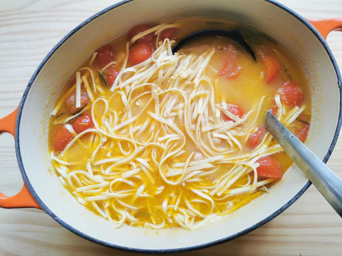 Fresh tagliolini added to chickpea soup in Dutch oven.