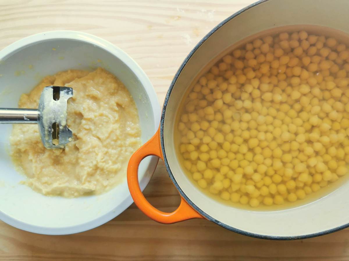 Cooked chickpeas in Dutch oven and puréed chickpeas in white bowl.