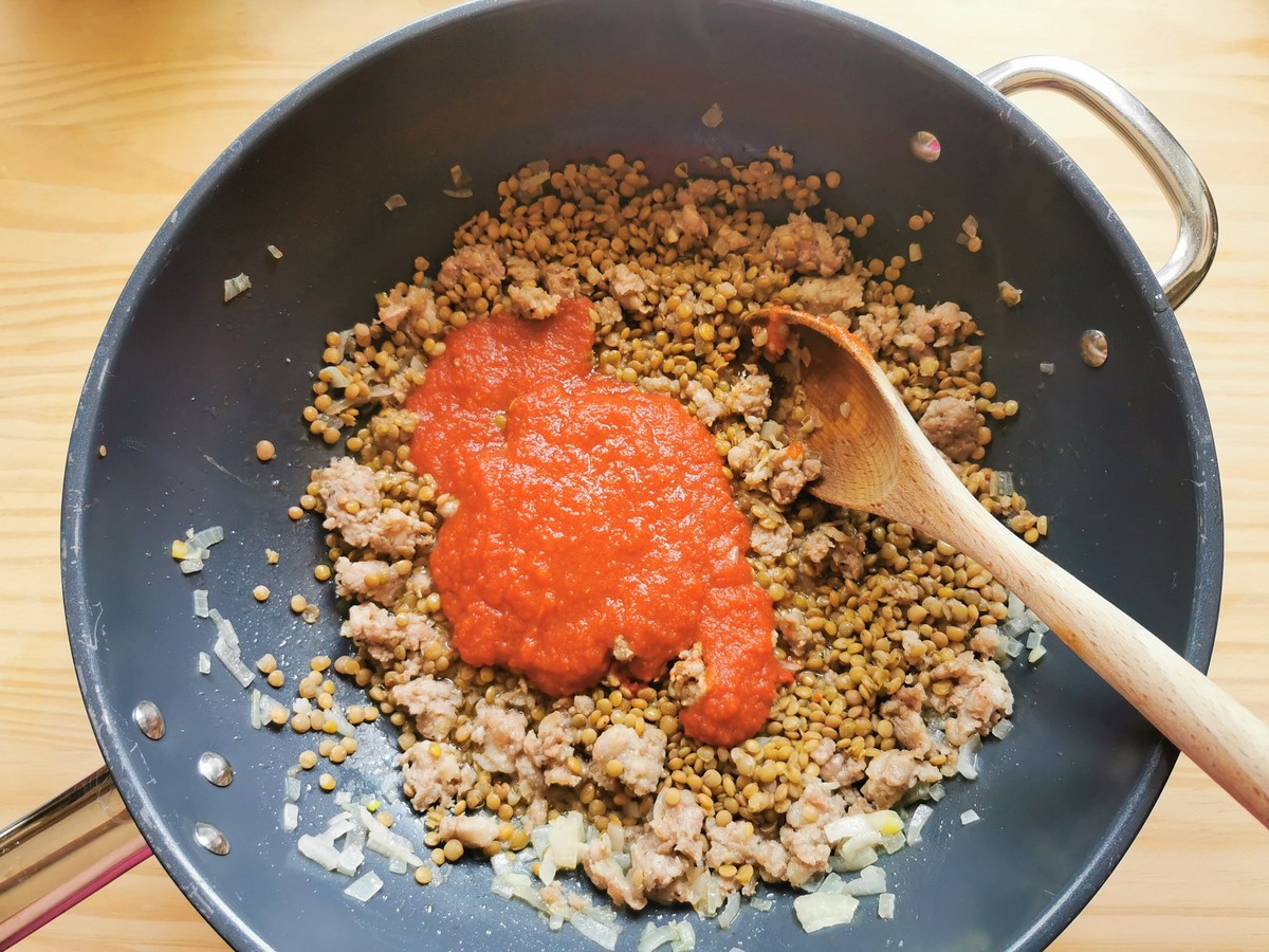 Tomato passata added to lentils, sausage and onion in skillet.