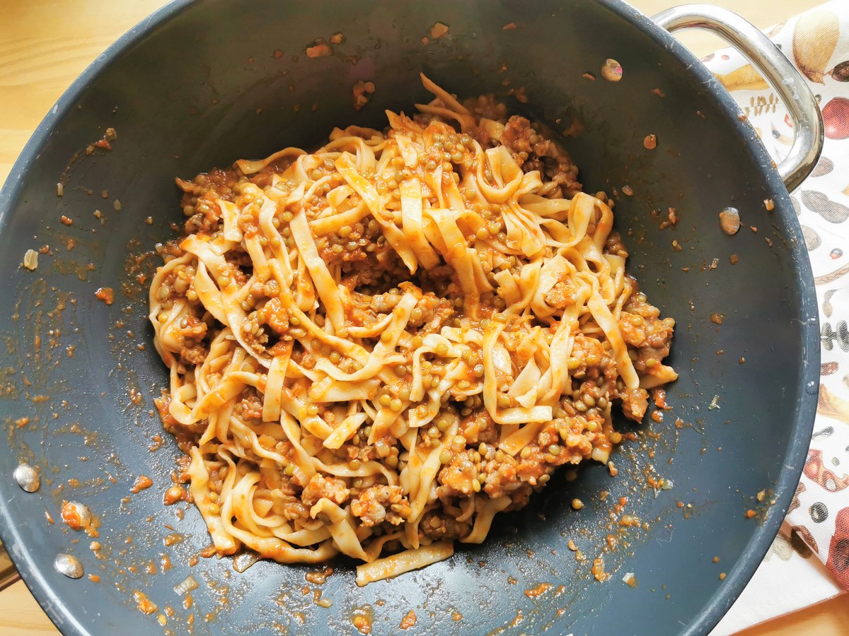 Cooked strangozzi mixed with lentil and sausage sauce in skillet.