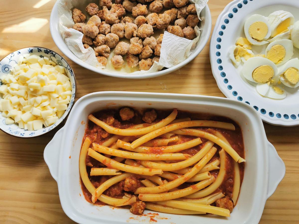 Cooked ziti in oven dish with porcini, tomato sauce and meatballs. Cubed cheese, had boiled eggs and more meatballs in separate bowls.