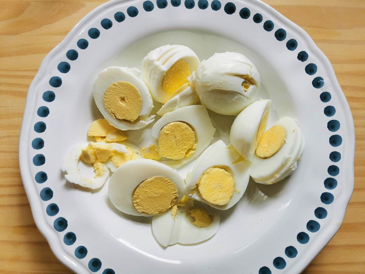 Hardboiled eggs cut into slices on white plate.