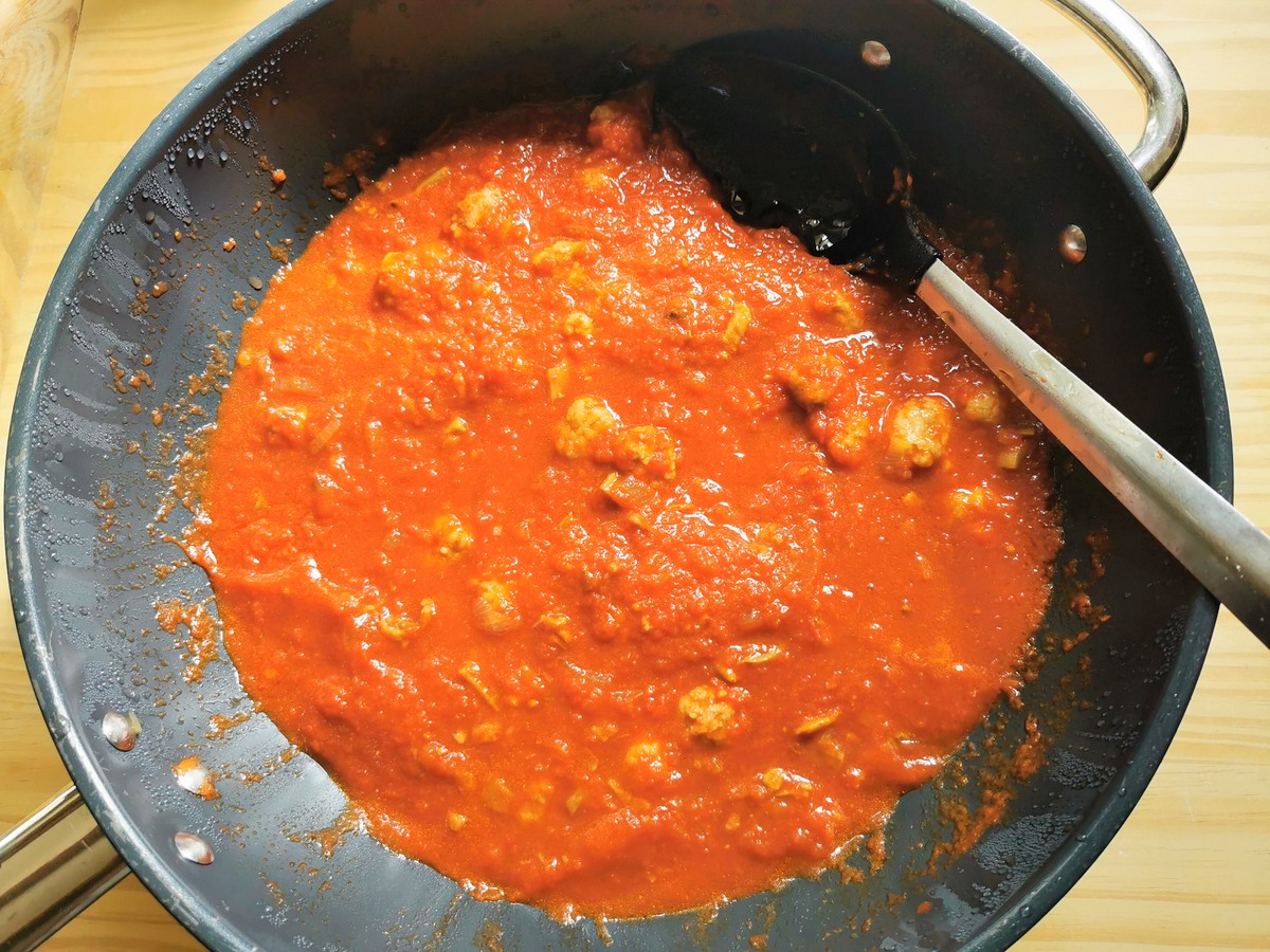 Porcini and tomato sauce with meatballs cooking in skillet.