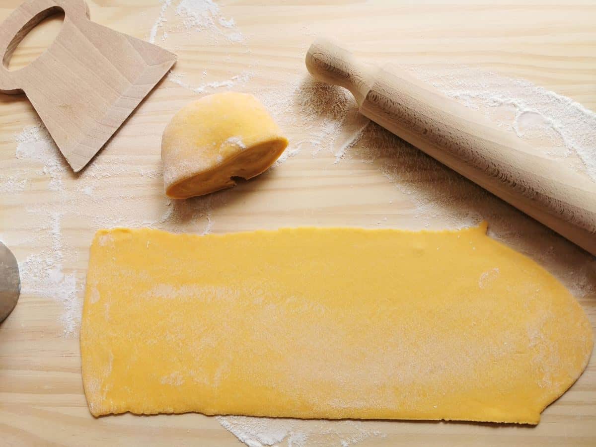 rectangular fresh pasta sheet on pastry board with rolling pin