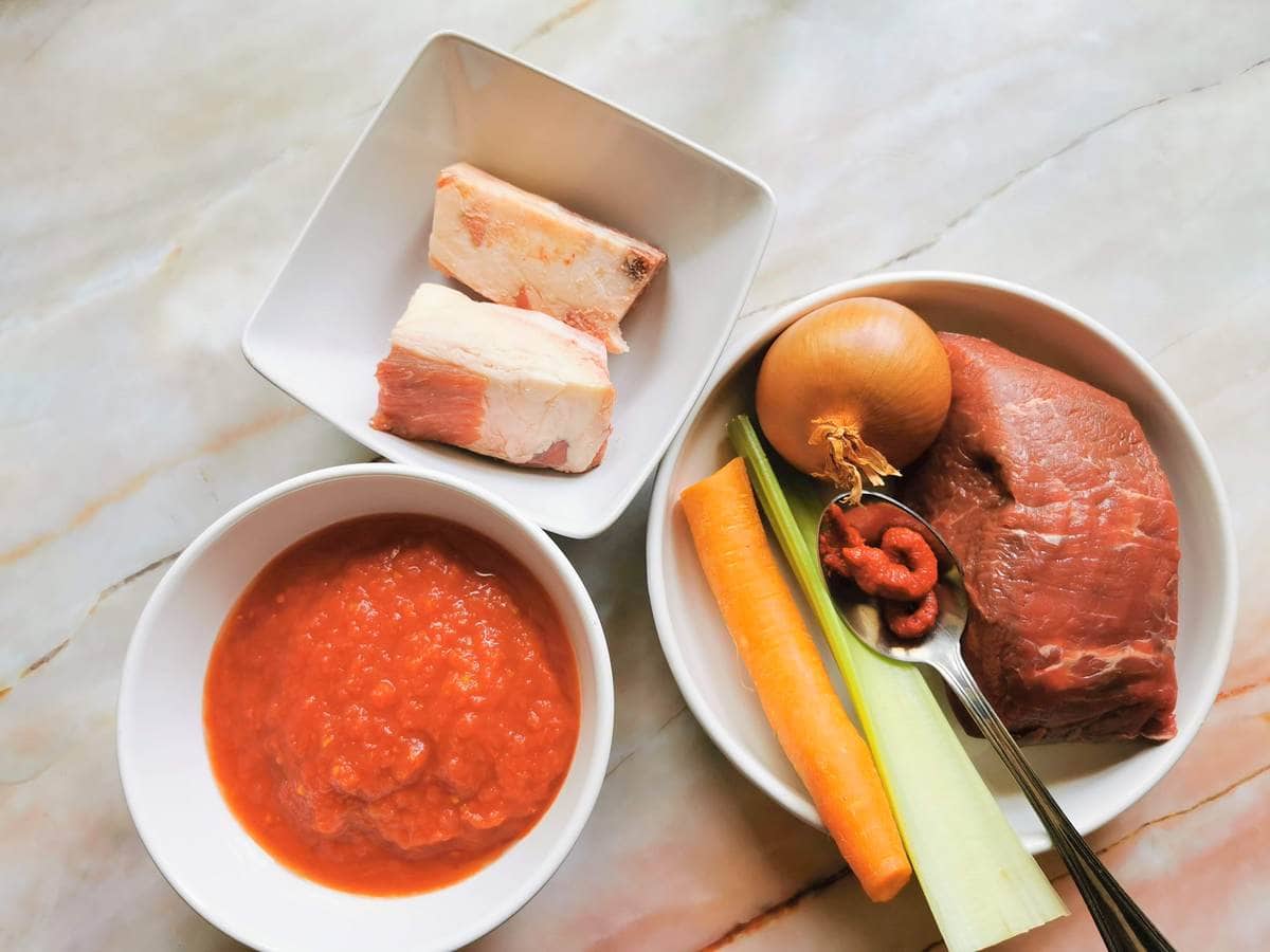 ingredients for meat sauce in white bowls