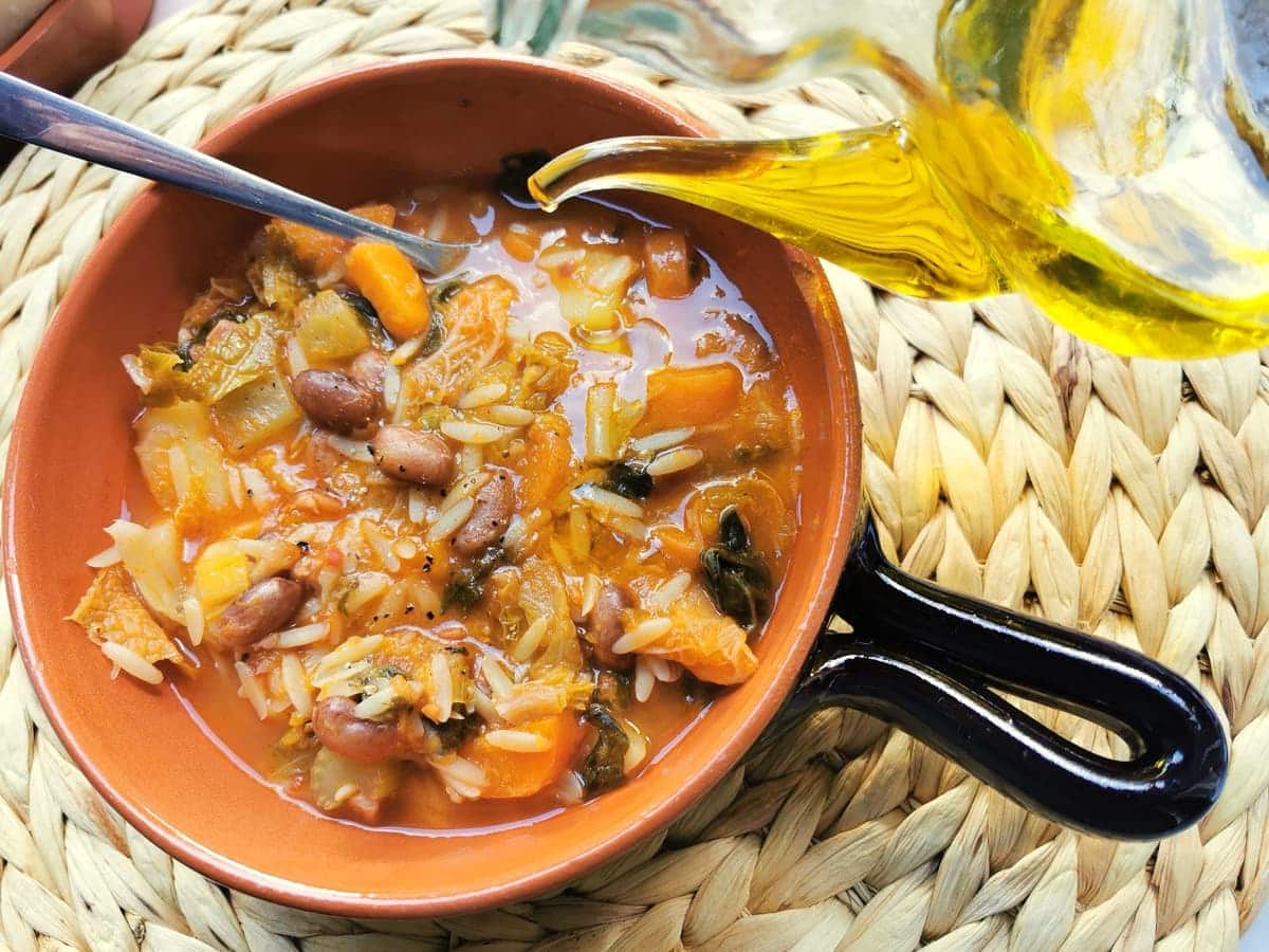Tuscan minestrone with orzo in terracotta bowl.