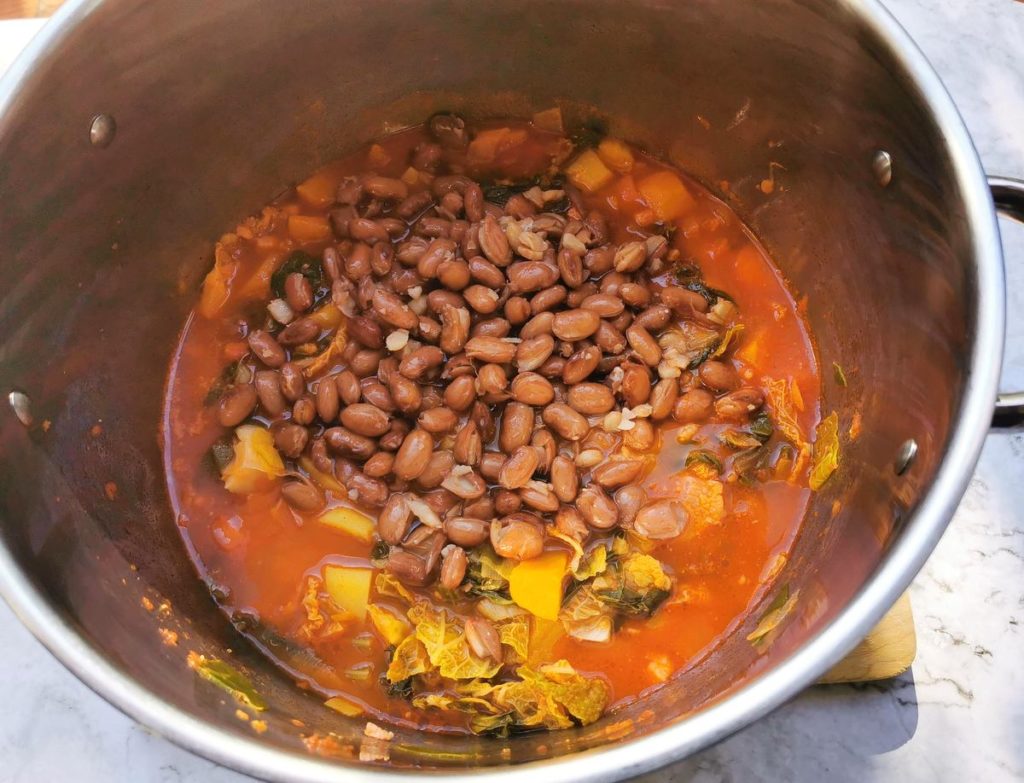 Cooked borlotti beans in pot with vegetables