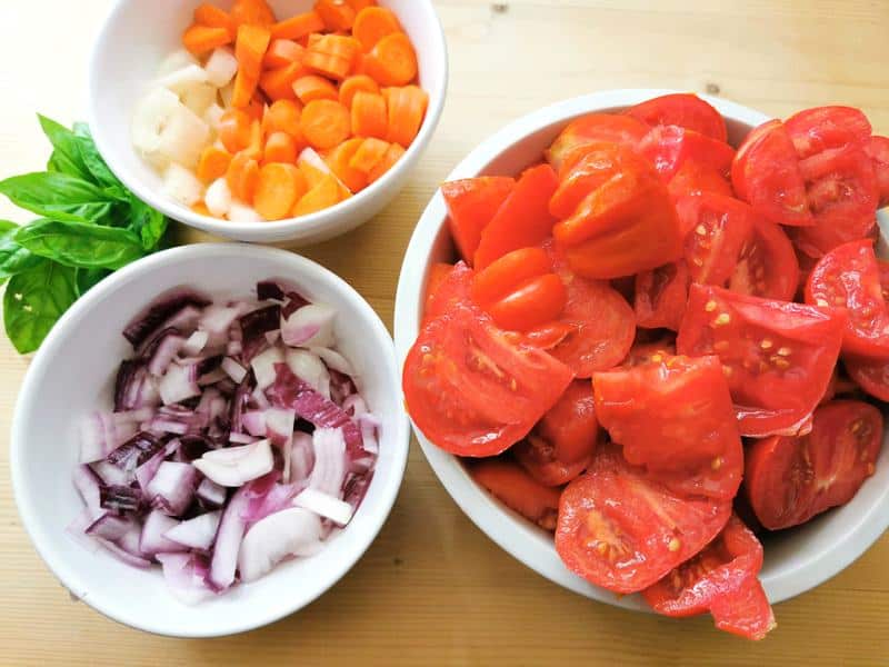 chopped tomatoes, onions, carrots and celery in white bowls