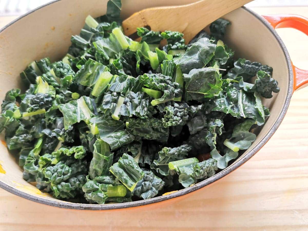 Fresh kale in Dutch oven on top of other veggies.