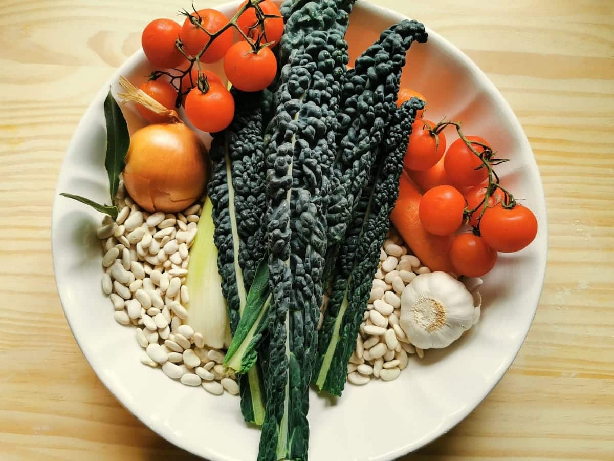 ingredients for Tuscan kale, white bean and pasta soup on white plate