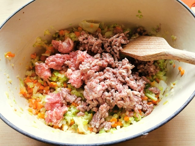 chopped onions, celery and carrots in Dutch oven with sausage and ground meat