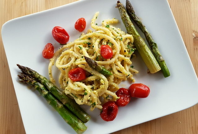 Tuscan pici pasta all'etrusca with asparagus and cherry tomatoes on white plate