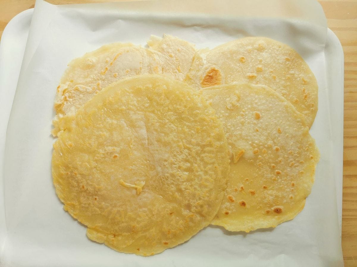 Ready testaroli pancakes on kitchen paper covered tray.