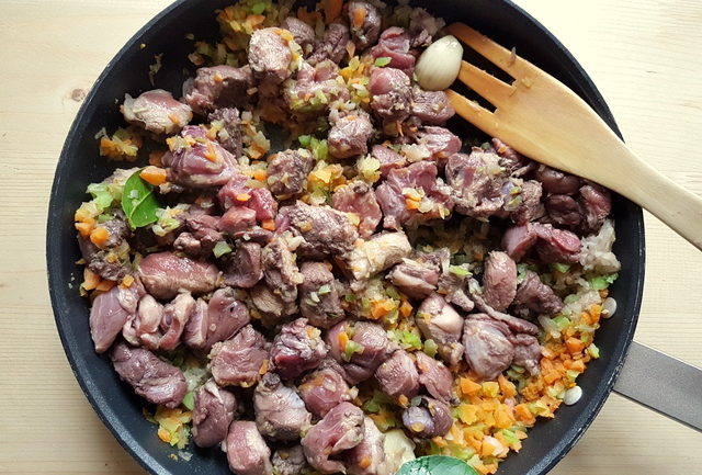 wild boar meat and vegetables cooking in a frying pan