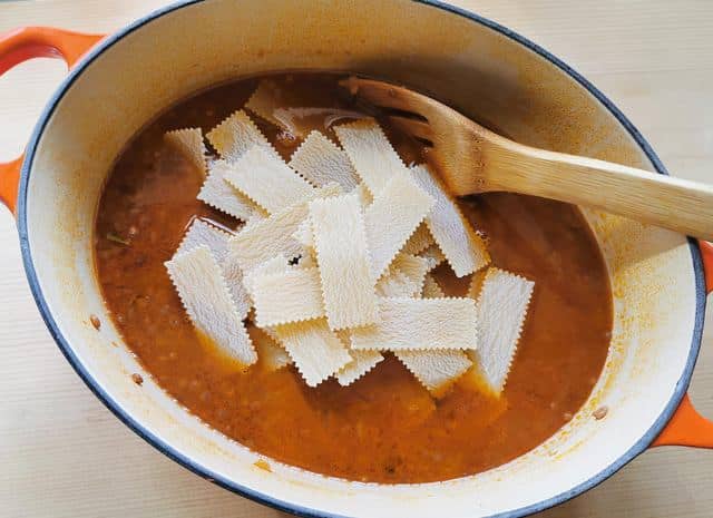 dried sagnarelli pasta added to the lentil soup in Dutch oven