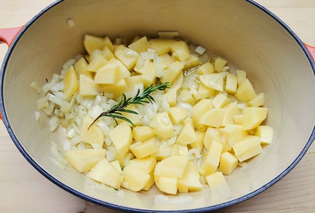 onions, rosemary and diced potatoes in Dutch oven