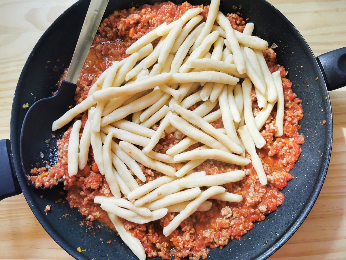 Cooked and drained homemade maccheroni in pan with veal ragu.