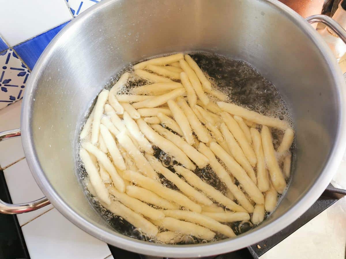 Homemade maccheroni cooking in boiling water in a large pot.