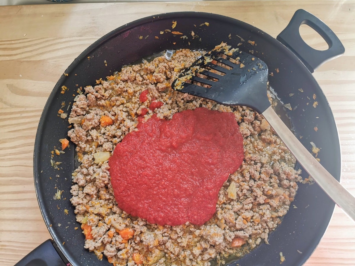 Tomato passata added to skillet with cooked ground veal and vegetables.