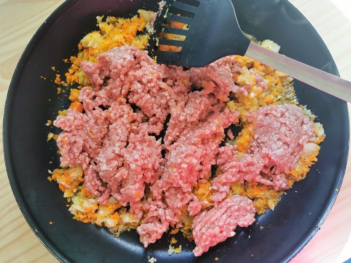 Uncooked ground veal in skillet with finely chopped onion, celery and carrot.